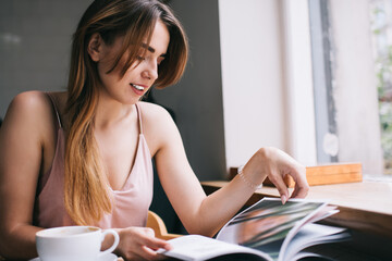 Teenage woman looking trough magazine at home