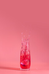 Glass of strawberry drink with splash. Summer art food concept on pink background.