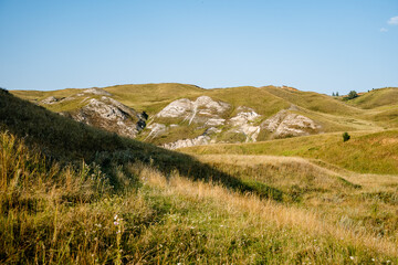nature of Russia, warm sunset light falls on the slopes of the Ural mountains, green grass on the...