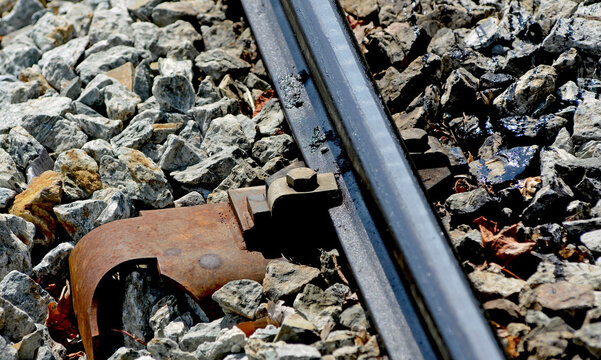 Dettaglio di una rotaia di funicolare a cremagliera: bullone con ruggine e grasso meccanico sulla massicciata ferroviaria. 