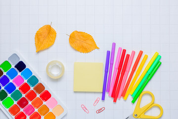 School supplies on a white checkered paper background. Back to school. New academic year begin. Place for text.Stationery set.Teacher's Day. Autumn