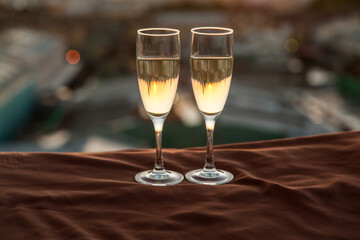 Two glasses of champagne on the background of city roofs at sunset