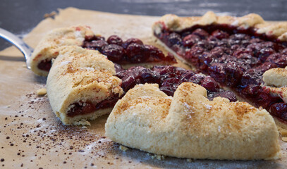 Summer homemade galette with cherries on parchment paper. Summer French open pie.