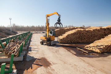 Industrial loader loads logs at a sawmill