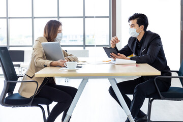 Fototapeta premium Business and social distancing sitting at the same table with a plastic shield.Office new normal lifestyle.