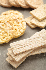Various types of healthy whole grain crispbreads on grey wooden background.