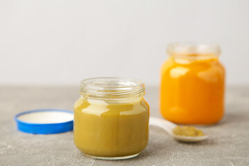 Glass jars with nutrient baby food on grey background