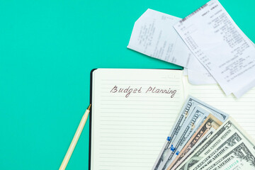 Budget accounting concept. Money, pen, receipts and notepad with handwritten words Budget Planning on green background, Top view with copy space