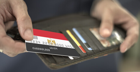 Man pulls plastic bank card with flag of Egypt out of his wallet, fictional card number
