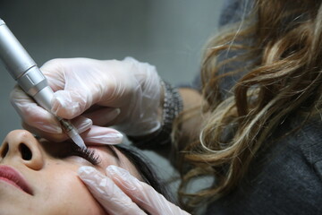 woman lying on couch at beauty salon with closed eyes and enjoying when cosmetologist making...