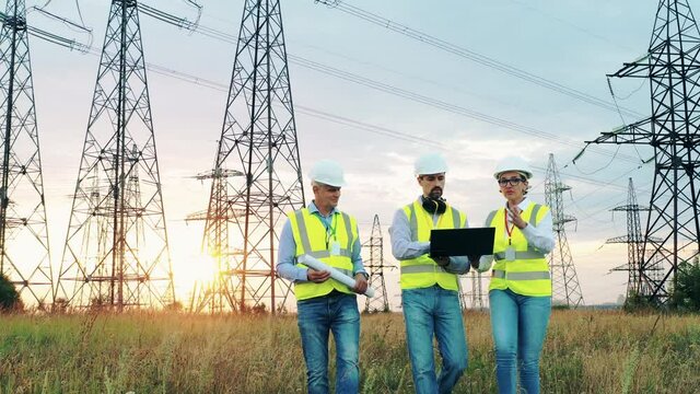 Field with transmission towers with engineers walking along it