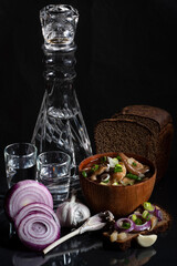 Composition with a decanter of vodka with chopped onions, garlic, bread, a wooden plate with mushrooms, a herring sandwich and black bread.