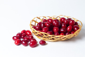 Dogwood on a white background. Wicker basket full of ripe red dogwood. Not many dogwoods are near. Gathering the summer harvest.