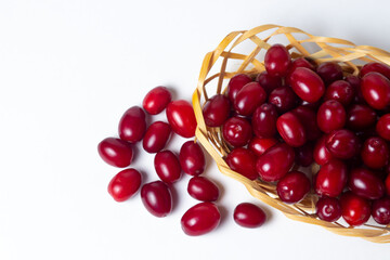 Dogwood on a white background. Wicker basket full of ripe red dogwood. Not many dogwoods are near. Gathering the summer harvest.