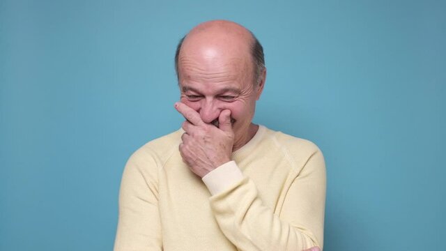 Senior man laughing and embarrassed giggle covering mouth with hands