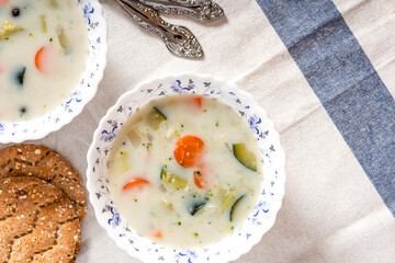 Creamy soup with vegetables in bowls on a white tablecloth top view. Vegetable vegetarian soup, rustic style. Free space for text. Tasty and healthy food.