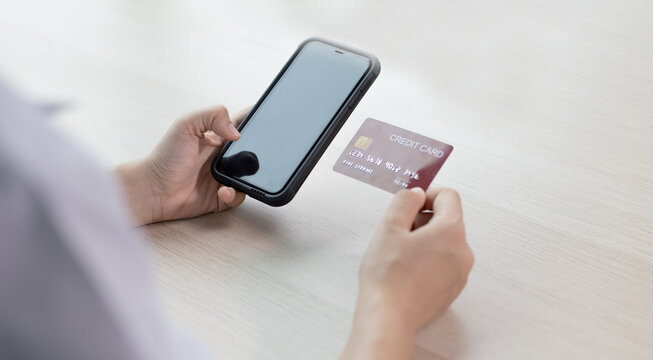 Young women hold credit cards to make purchases online on mobile phone