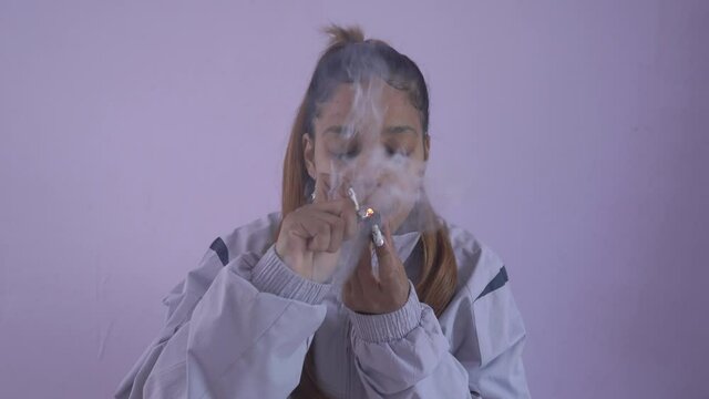 Young woman smoking marijuana at home