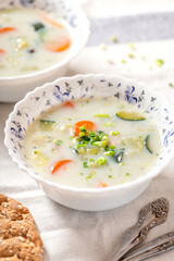 Creamy soup with vegetables in white bowls close-up. Vegetable vegetarian soup, rustic style. Tasty and healthy food.