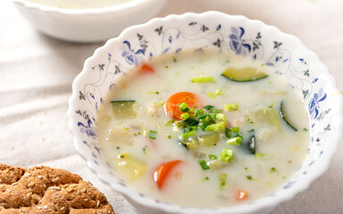 Creamy soup with vegetables in white bowls close-up. Vegetable vegetarian soup, rustic style. Tasty and healthy food.
