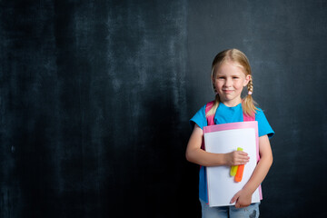 Schoolgirl with a briefcase on the background of a school board for chalk. Back to school concept with copy space.