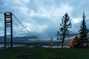 Cable-stayed bridge over a mountain river at dusk, Altai, Siberia