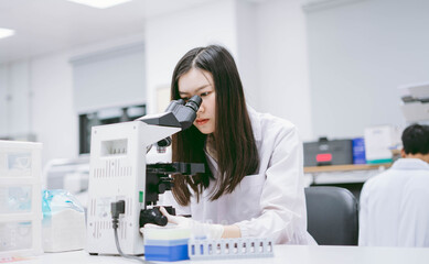 young female medical scientist looking at microscope in laboratory.