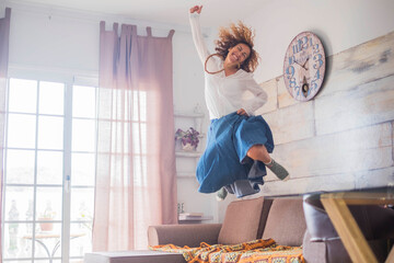 Joyful lifestyle and success concept for female people - woman jumping on the couch for happiness -...