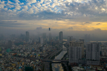 Fototapeta na wymiar Beautiful aerial photo of colorful sunrise and morning fog in Ho Chi Minh City featuring the canal, bridges Saigon River and high rise buildings obscured by low cloud