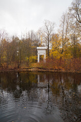 Fototapeta na wymiar White arch among autumn trees reflected in a pond
