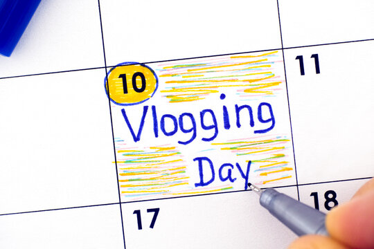 Woman fingers with pen writing reminder Vlogging Day in calendar