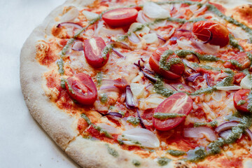 Vegan fresh baked pizza with cherry tomatoes, onion, garlic and basil pesto