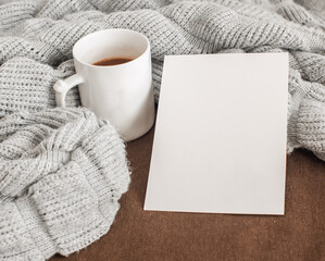 cup of coffee and paper on brown paper background. cozy gray fluffy sweater