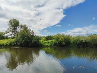 green river bank against the background of a beautiful blue sky with clouds