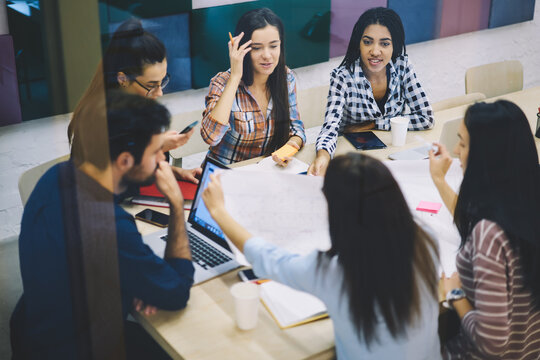 Skilled male and female designers discussing details about office building project while working with sketches on informal meeting,team of engineers productively collaborating while brainstorming