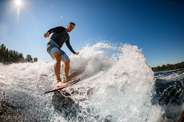 male wakesurfer rides the wave on surfboard
