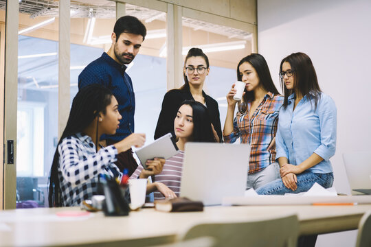 Crew of young graphic designers creating main concepts for new office building and making research on digital tablet connected to 4G internet,male and female having informal meeting during conference