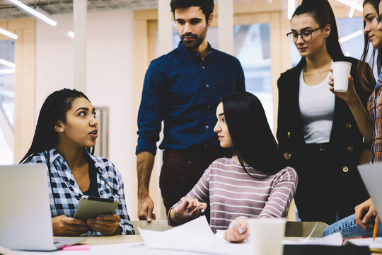 Creative young male and female students actively preparing together to upcoming examination in university and searching useful information on websites via touchpad connected to internet indoors