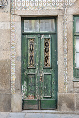 Fototapeta na wymiar Derelict Weathered Ornate Wooden Doors, Bordered By Tiles (Azulejos), Braga, Portugal