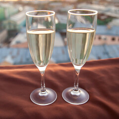 Two glasses of champagne on the background of city roofs at sunset