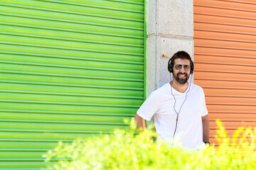 Cool trendy funny beard man in headphones listening music on colored background.