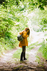 Naklejka na ściany i meble woman in yellow raincoat walking by rainy forest