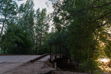 Fototapeta na wymiar A small metal bridge near the river