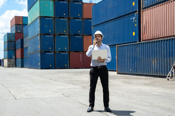 Businessman standing and using walkie talkie checking stock into container for loading in shipping...