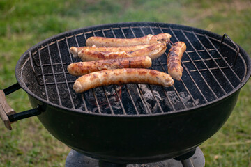 Delicious sausages frying on a grill outdoors.