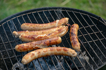 Delicious sausages frying on a grill outdoors.