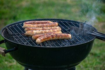 Delicious sausages frying on a grill outdoors.