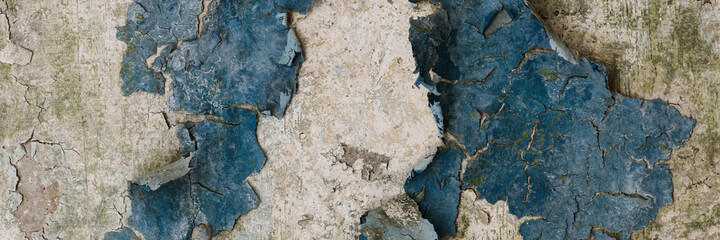 Peeling paint on the wall. Panorama of a concrete wall with old cracked flaking paint. Weathered rough painted surface with patterns of cracks and peeling. Wide panoramic grunge texture for background