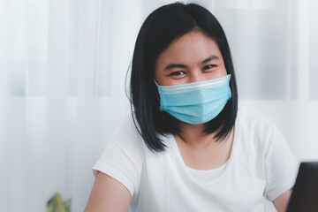 Young business woman smiling under mask working from home  while quarantine from coronavirus  outbreak