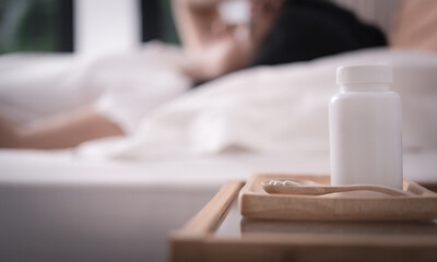 Beautiful  woman  get headache and cold lying down in bed  with pill bottle on table side,healthy and medicine concept